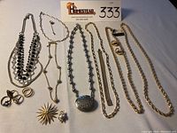 Full assortment of jewelry including necklaces, earrings, pins, and rings laid out on a cloth background.