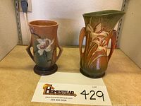 Front view of two Roseville vases with floral designs, showing size and color contrast.