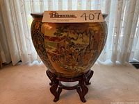 Front view of the large Satsuma fish bowl on the rosewood stand showing detailed hand-painted designs and the auction lot number.