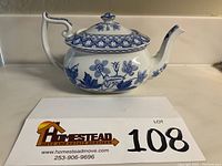 Front and side view of Spode blue and white floral geranium teapot with lid showing spout, handle, and floral pattern.