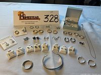 Full display of sterling silver earrings on cards and loose, with bracelet and band/pendant visible, showing variety and condition