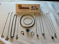 Photo of entire assortment of sterling silver necklaces, rings, and bracelets arranged on a white cloth showing all the items together for a full overview of the lot.
