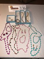 Overview of the assortment of Swarovski Touchstone crystal jewelry on white surface including necklaces, bracelets, earrings in original blue boxes.