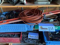 Wide view of assorted tools including orange extension cord, levels, and toolboxes with sockets and wrenches on a shelf.