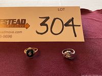 Front-facing view of both rings on burgundy fabric under lot marker