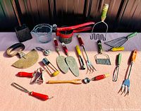 Photo displaying full collection of antique kitchen utensils including masher, graters, peelers, scrapers, forks with painted wood handles and metal parts.