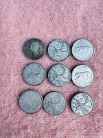 Nine Canadian circulated silver quarters laid out on a pink surface showing both obverse and reverse sides with visible wear and age marks.