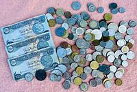 Full assortment of foreign coins and four currency notes displayed on a pink cloth.