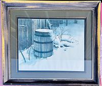 Framed print showing a wooden barrel covered in snow next to weathered wood siding and tree branches in snow.