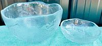 Two clear glass leaf design bowls, smaller bowl nested inside larger bowl, showing textured leaf surface detail and organic rims.