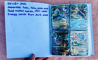 Open binder showing handwritten note '25 x 8 = 200 Japanese holo, Holo, 2012-2018 Gold metal cards, 1995-2020 Energy cards from 2013-2023' and first page of cards.