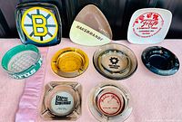 Overview photo of vintage ash tray collection including Boston Bruins, Hausbrandt, Frigo, and other logos on assorted shapes and colors
