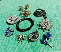 Group showing all jewelry pieces on green fabric background, highlighting color and design variety