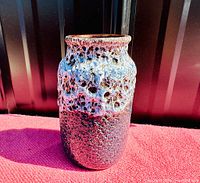 Full view of the vase showing the textured fat lava glaze in red and blue tones.
