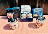 Four Royal Worcester porcelain egg coddlers displayed outdoors; three with original blue boxes and silver lids, one without box. Three boxes are branded Royal Worcester Flameproof Porcelain.