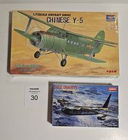 Photo of two airplane model kits, one sealed with colorful box art of Chinese Y-5, and one smaller box with B-52 Stratofortress model kit showing cloud and mountain scene.