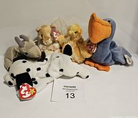 Front view of five Beanie Baby plush toys including spotted Dalmatian, guinea pig, yellow chick, blue pelican, and gray antelope, all with original Ty heart-shaped tags