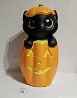 Front view of black cat blow mold with jack-o'-lantern pumpkin. The cat with green eyes peeks out of the pumpkin with a happy face.