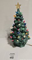 Front view of the ceramic Christmas tree decorated with removable colored bulbs and star topper.