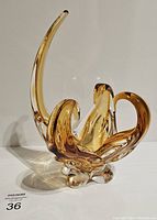Front and side angle view showing the curving, elongated tips of the amber glass dish with thick rounded base.