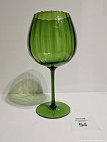 Front view of the green Empoli Italian art glass brandy snifter with shadow cast on white background.