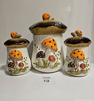 Front view of three ceramic mushroom canisters with decorated lids