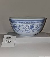 Side view of Pyrex Brittany Blue mixing bowl showing floral blue pattern on white glass.