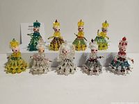 Ten handmade girl ornaments crafted from safety pins and beads shown in two images from slightly different angles.