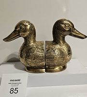 Pair of brass duck bookends front view together showing their details and design.