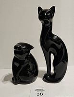 Full view of two black ceramic cats, one tall and slender and one short and rounded