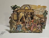 Front view of vintage German nativity scene in 3D pop-up form showing figures arranged around stable with palm trees and star featuring Gloria in Excelsis Deo banner.
