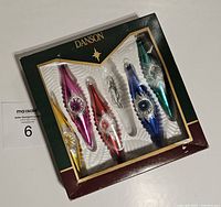 Five Danson glass Christmas tree ornaments in original packaging showing pink, red, blue, green, and yellow colors with lot tag number 6