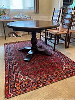 Full view of rug laid under round pedestal table showing overall pattern and dimensions.