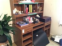 Front left angle view showing the desk with removable bookcase above and several open shelves and storage compartments below.