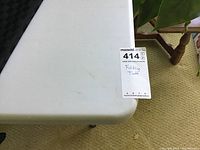 Close-up of the white plastic tabletop corner with the MaxSold label for identification.