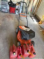Front view showing mower deck, grass bag and gas cans