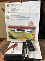 Photo showing the Sony DVD player with remote control, manual, and The Devil Wears Prada DVD disc placed on top of the Sony device, alongside the box of the GE Slim Spacemaker CD player and radio.
