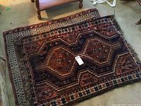 Photo showing navy and brown geometric patterned area rug with fringe edges.