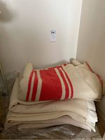 Stack of three wool blankets showing the red and white striped blanket on top of two lighter colored beige blankets.
