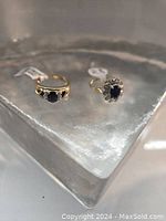 Two rings displayed on a glass block platform, showing overall appearance and original tags attached