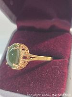 Side angle view of ring in velvet box showing raised platform and filigree detail