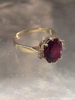 Oblique view showing deep red garnet in prong setting on yellow gold band