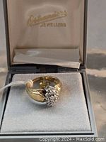 Front view of ring in gray jewelry box showing diamond cluster