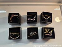 Six gold-tone costume necklaces, new in box, each with different stone accents and designs.