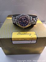 Watch positioned on yellow-striped Breitling box showing brand logo and label