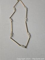 Full necklace laid flat showing alternating gold bars and pearl beads