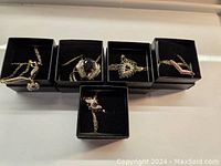 Five costume jewelry necklaces in black boxes with gold-tone chains and various stone pendants.