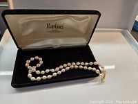 Full view of the freshwater pearl necklace arranged in a black velvet presentation box with satin lining.