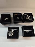 Photo showing all five jewelry sets including rings, earrings and necklaces in black presentation boxes
