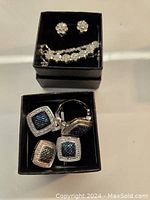 Photo showing both jewelry sets inside separate black boxes, including earrings, rings, and a necklace.